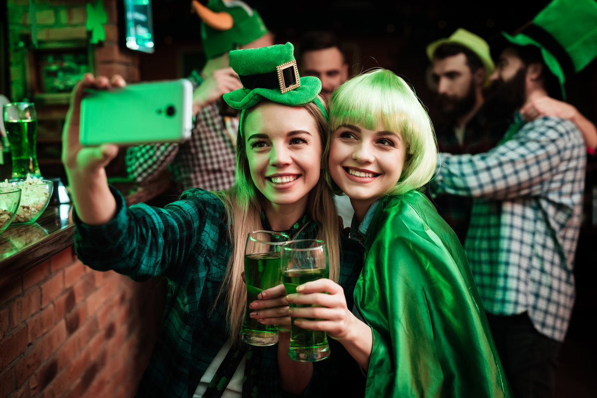 Two girls in a wig and hat make selfi at the bar.